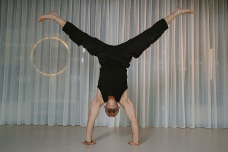 A man stands on his hands. Athletic man performs arm strength exercise