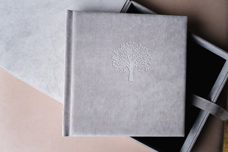 A photo book in a grey cloth cover lies on the box. the concept of creating books and albums from...