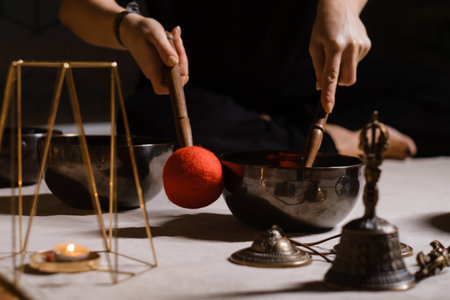 Practicing sound healing with singing bowls during a meditative session at a serene indoor setting with soft lightingの写真素材