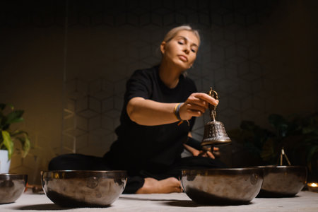 Practicing mindfulness and meditation with singing bowls in a tranquil indoor setting during a holistic wellness sessionの写真素材