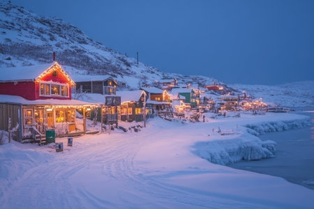 A quaint village blanketed in snow showcases vibrant, twinkling lights adorning cozy cabins. The icy coastline gently reflects the enchanting glow as twilight descends, creating a serene, magical atmosphere.の素材