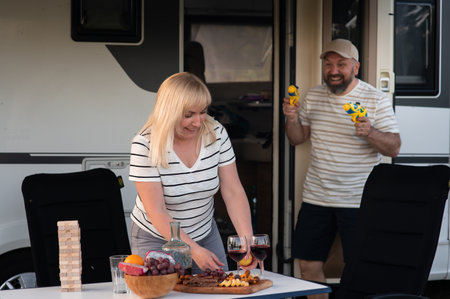 Outdoor relaxation and fun with board games and snacks near a camper during sunset with friends enjoying wine and laughterの写真素材