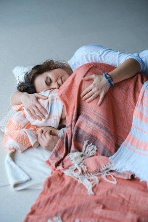 Two individuals share a warm embrace while wrapped in colorful blankets, enjoying a tranquil morning...