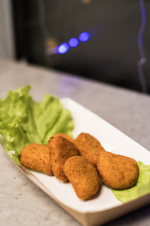 A platter displays several crispy chicken nuggets arranged on a bed of vibrant green lettuce,...