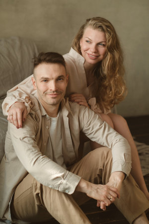 Couple relaxing together indoors, sharing a moment of joy and connection, surrounded by soft lighting and neutral tones, creating a warm atmosphereの写真素材