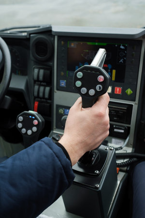 A pilot skillfully adjusts the control stick of a vessel in challenging weather conditions. The dashboard displays various navigational devices while the pilot focuses on steering.の写真素材
