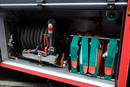 Firefighting equipment is displayed in a fire truck compartment, showcasing various hoses, valves,...