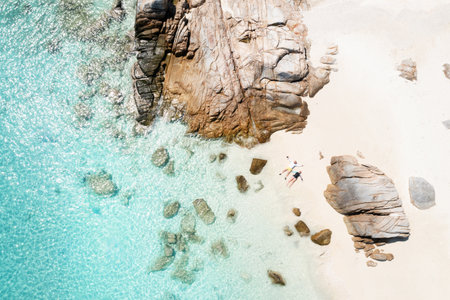 A couple in love is relaxing on a beach with white sand and large rocks on the island of Lang Tengah, Terengganu, Malaysia.の写真素材