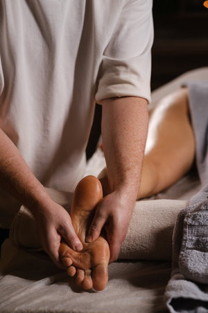 Relaxing foot massage therapy session in a calming spa environment during evening hoursの写真素材