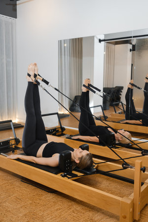 Stretching and strengthening legs during a Pilates session focused on core stability in a bright...