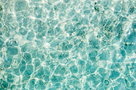 Clear turquoise water reflecting sunlight along a serene beach in the afternoon, inviting relaxation...