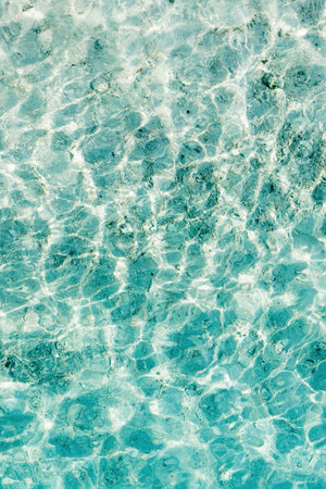 Clear turquoise water reflecting sunlight creates beautiful patterns in a shallow setting during a bright afternoonの写真素材