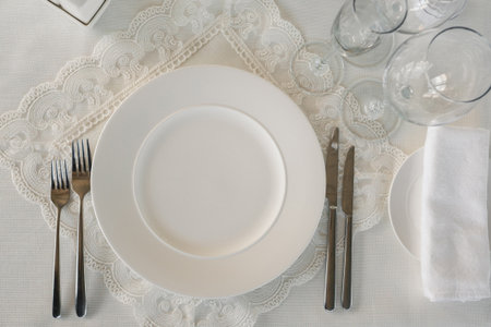 Elegant dining setup featuring pristine white plate and polished cutlery on a delicate lace...
