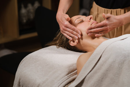 Relaxing facial massage at a spa with a calm atmosphere and soothing lighting, promoting wellness and rejuvenation in a tranquil settingの写真素材