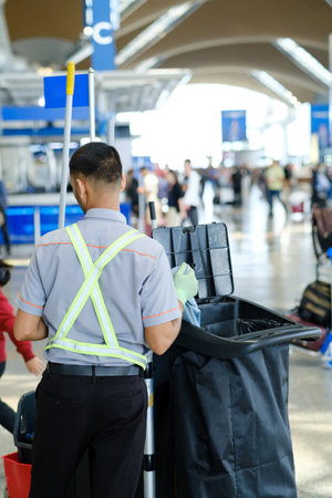 Workers maintain cleanliness and order at a busy airport terminal while travelers move about during...