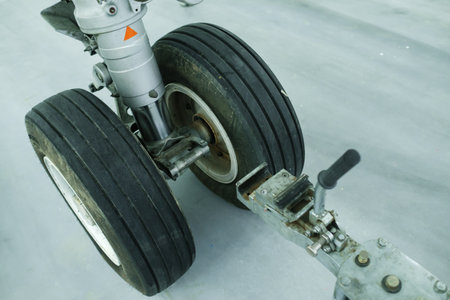 Close view of aircraft landing gear with worn tires and hydraulic system parts on a clean maintenance floor inside an aircraft hangar, showcasing the intricate design and engineering involved.の写真素材