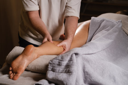 Therapeutic massage session focusing on leg muscles for relaxation and stress relief in a cozy treatment roomの写真素材