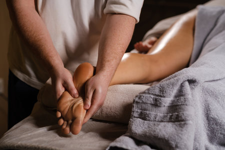 The master massages the feet of the foot. The expert foot massage technique, performed in a calm spa environment, is aimed at relaxing and relieving stress for the client.の写真素材