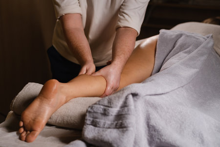Massage therapist provides a relaxing leg massage in a serene spa environment during a wellness sessionの写真素材