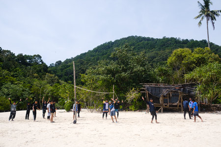 Redang Island, MALAYSIA, July 27, 2025. Local tourists play volleyball on turtle beach and enjoy a sunny day next to the tropical jungle on the hillsのeditorial素材