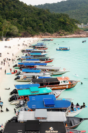 Redang Island, MALAYSIA, July 26, 2025. Tourist boats are lined up on Turtle Beach, and tourists are enjoying a sunny day against the backdrop of a bright turquoise seaのeditorial素材