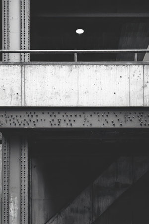 A close-up view of a bridge's structural components showcases the interplay between concrete and metal. The emphasis is on industrial design features like rivets and beams, with muted tones enhancing the architecture's strength and durability.の素材