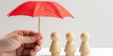 Wooden figures under an umbrella. Family and property insurance concept.の素材