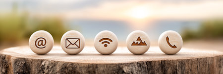 Wooden communication icons on a tree stump symbolizing contact information, communication, customer support, and business interactionsの素材