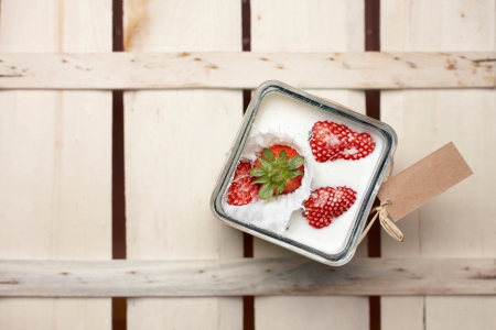 Overhead view of a ripe red strawberry being dropped into a container of milk with a splashの写真素材