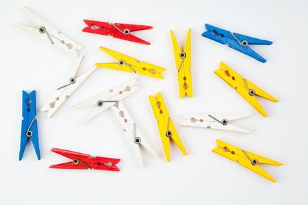 colored plastic clothespins spread out near one another on a white backgroundの写真素材
