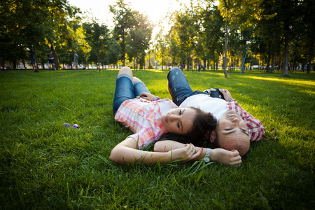 cheerful young couple relaxing in the park on the grass and in the cityの写真素材