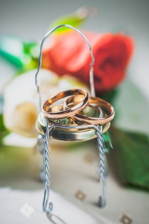 Miniature wedding rings lie on a toy studio wireの写真素材
