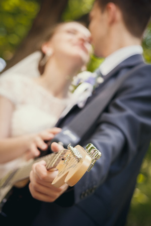 Young beautiful wedding couple electric guitar in the parkの写真素材