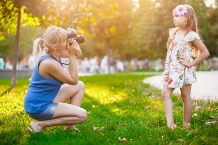 Mother photographing her daughter in park