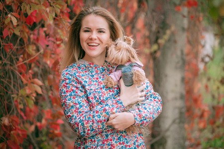 Young beautiful woman with Yorkshire Terrier, against green of summer park.の写真素材