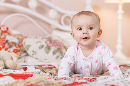 A newborn baby child is laying down on a soft pink isolated background and sleeping with a hat on. The girl is laying belly downの写真素材