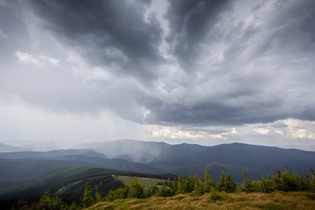 storm clouds over the mountains and small birds in a dark skyの写真素材