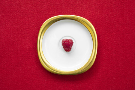 Raspberry placed on a golden white dish with isolated red background.の写真素材