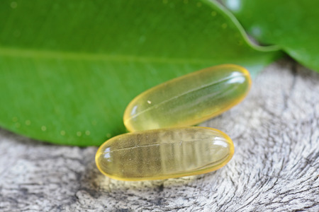 Cod liver oil omega 3 gel capsules isolated on wooden backgroundの写真素材