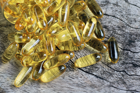 Cod liver oil omega 3 gel capsules isolated on wooden backgroundの写真素材