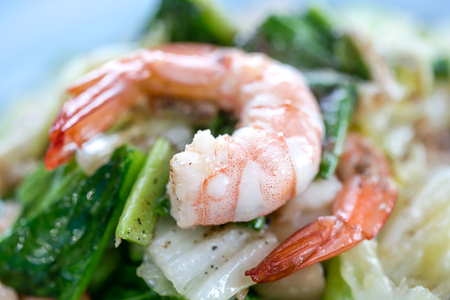 chopped raw vegetables in a frying pan with grilled shrimpの写真素材