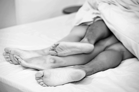 Close up of male and female feet on a bedの写真素材