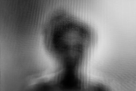 woman standing behind blurry glass/behind the window