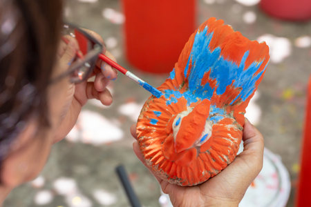 painting with acrylic colors on a clay product in a pottery workshop