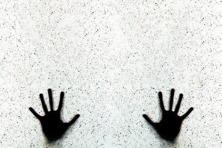 Silhouette of a man's hand on a white wall.の写真素材