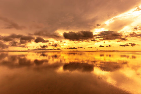 beautiful sunset on the beach, sea and sky reflection in waterの写真素材