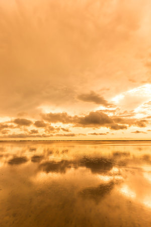 Beautiful sunset on the beach with clouds reflected in the water.