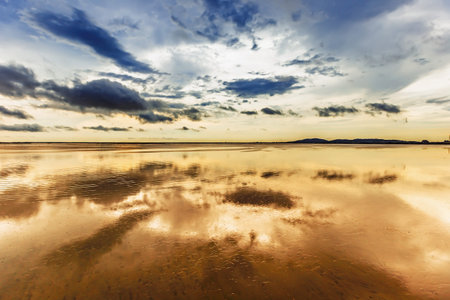 Sunset on the beach with reflection of clouds in the water.
