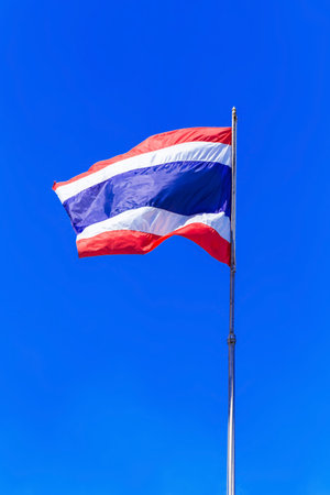 Thailand national flag waving in the wind on blue sky background.