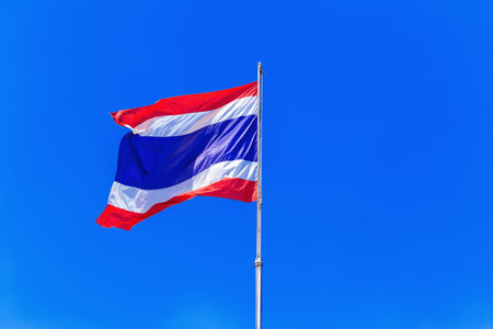 Thailand flag waving in the wind against blue sky background with copy space
